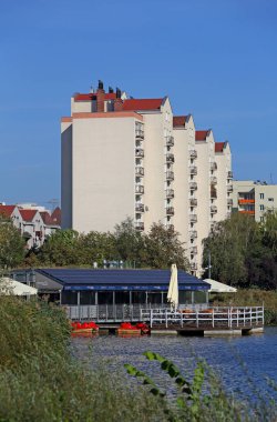 Varşova, Polonya - 24 Eylül 2024: Praga-Poludnie bölgesindeki Goclaw konutlarında küçük bir göl kenarındaki apartman ve eğlence tesisleri.