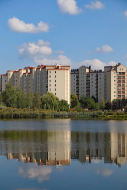 Varşova, Polonya - 21 Eylül 2024: Praga-Poludnie 'nin bir alt bölgesi olan Goclaw malikanesinde, güneşli bir günde bir grup apartman bloğu ve gölün sularındaki yansımaları görülebilir.