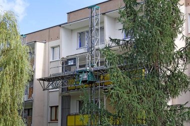 Varşova, Polonya - 8 Ağustos 2023: Yenilenen bir binanın cephesi. Balkonları modernize etmek ve ön cephe üzerinde çalışmak için kullanılan ekipman görülebilir. Goclaw konutları.