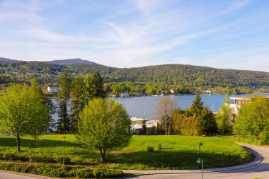 Velden Am Worthersee, Avusturya - 4 Mayıs 2023: Göl manzaralı, ormanlık tepeler ve güzel kırsal kesimde evler, burası tatil için harika bir yer.