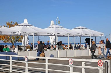 Sopot, Polonya - 12 Ekim 2024: Güneşli bir sonbahar günü olduğu için açık bir kafe işletiliyor, neredeyse tüm koltuklar dolu.