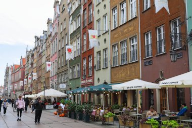 Gdansk, Polonya - 10 Ekim 2024: Çeşitli tarihi binalar ve renkli cepheleriyle geleneksel mimari. Binaların yanında açık hava restoranları var..