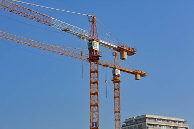 Varşova, Polonya - 26 Ekim 2024: İnşaat alanında çalışan iki vinç. Turnaların patlamaları, güneşli mavi gökyüzüne karşı görülebilir..