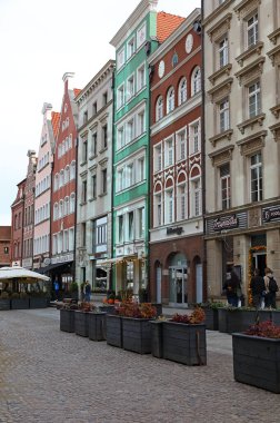 Gdansk, Polonya - 10 Ekim 2024: Şehrin tarihi, popüler ve turistik kesimindeki kaldırımlı bir sokakta evler ve renkli cepheler.