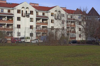 Varşova, Polonya - 18 Ocak 2025: Güneşli bir günde Praga-Poludnie bölgesindeki Goclaw konutlarında çimenli bir oyun alanının arkasındaki apartman bloğu.