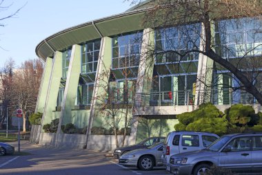 Varşova, Polonya - 20 Ocak 2025: Halka açık yüzme havuzuna ev sahipliği yapan binanın dış görünümü. Binanın yanında bir park yeri var ve birkaç araba oraya park edilmiş. Goclaw konutları 
