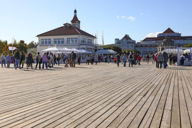 Sopot, Polonya - 12 Ekim 2024: Birçok insan güneşli bir sonbahar gününde Baltık Denizi 'ndeki ahşap iskele boyunca yürür.