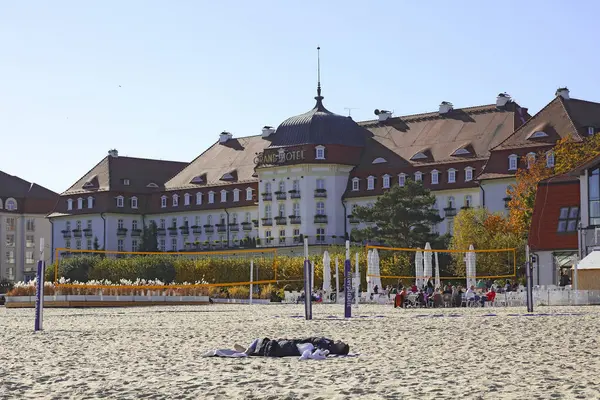 Sopot, Polonya - 12 Ekim 2024: 5 yıldızlı Sofitel Grand Sopot Oteli Gdansk Körfezi 'nin kumlu sahilinin kenarında yer almaktadır. Otel binası 1927 'den kalma. İnsanlar sahilde dinleniyor.