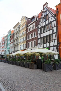 Gdansk, Polonya - 10 Ekim 2024: Çeşitli tarihi binalar ve renkli cepheleriyle geleneksel mimari. Binaların yanında açık hava restoranları var..