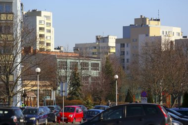 Varşova, Polonya - 10 Şubat 2025: Otomobil parkının arkasında ve blokların arasında Goclaw mahallesinde karsız kış mevsiminde okul cephesinin bir parçası görülebilir..