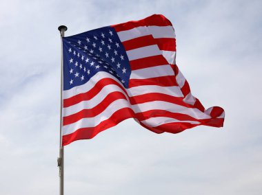 Amerika Birleşik Devletleri 'nin ulusal bayrağı bulutlu bir gökyüzünde bayrak direğinde dalgalanıyor..