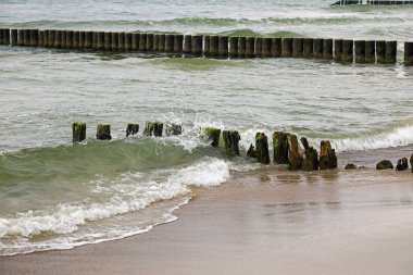 Üstronie Morskie, Batı Pomerania, Polonya 'daki Baltık Denizi kıyısındaki dalgaların zararlı etkilerinden korunmak için deniz tabanına sürülen yıpranmış dalgalar hala sahili koruyor..