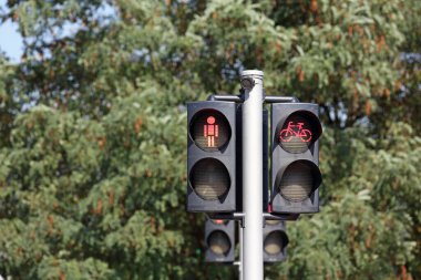 Yayalar ve bisikletçiler için trafik ışıkları var. Trafik ışıklarında yayalar ve bisikletçiler için kırmızı ışık yandı. Bir yayanın ve bir bisikletçinin figürü görünür.