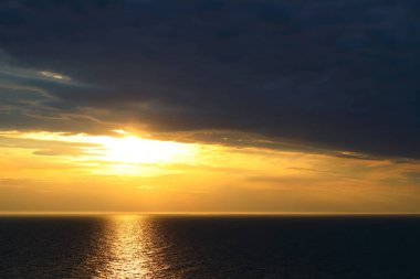Ufuktaki bulutlu gökyüzü ve Ustronie Morskie, Batı Pomerania, Polonya 'daki batan güneş Baltık Denizi üzerinde parlıyor.
