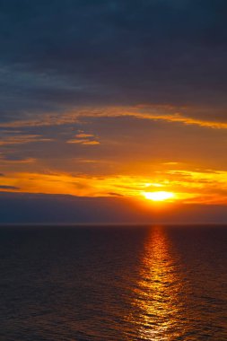 Ustronie Morskie, Batı Pomerania, Polonya 'da bulutlu gökyüzü ve batan güneş Baltık Denizi üzerinde parlıyor.
