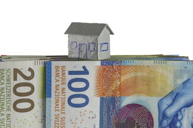 CHF banknotlarının üzerine cilalanmış kağıt bir ev modeli yerleştirilir. Bu tema, çeşitli finansal konuları göstermek için kullanılabilir.