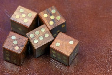 Deri bir arka planda ahşaptan yapılmış beş zar var. Bu tema çeşitli finansal, kumar, şans ve risk temaları için kullanılabilir..