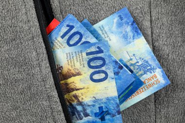 Üzerinde İsviçre frangı olan tüylü bir fermuar cebi. Bu tema, çeşitli finansal konuları göstermek için kullanılabilir.  