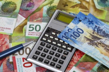 İsviçre banknotları ve aralarında kısmen görünür bir hesap makinesi var. Bu tema, çeşitli finansal konuları göstermek için kullanılabilir.