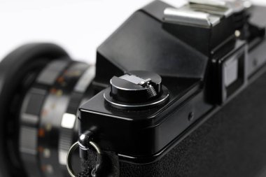 Eski model 35 mm 'lik mercekli bir SLR kamera, film geri sarma düğmesi görünür.