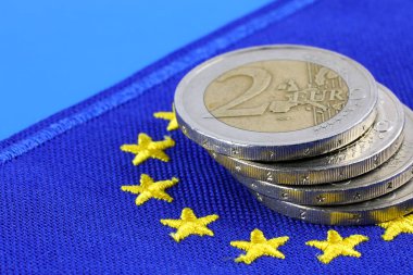 Bu, Avrupa Birliği 'nin para birimidir. Avrupa bayrağı ve iki avroluk bozuk para yığını. Bu tema çeşitli finansal konuları göstermek için kullanılabilir.