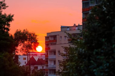 Akşamları, güneş Varşova 'daki Goclaw konutlarının bloklarının arkasında yavaşça batarken gökyüzü, binaların cepheleri ve hatta ağaçlar batan güneşin renkleriyle renklenir..