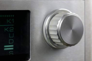 Eski bir analog radyo alıcısının ön panelinin bir parçası, ayar düğmesi ve ayar ölçeğinin parçası görünür..