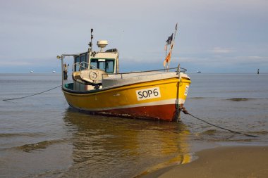 Sopot, Polonya - 9 Ekim 2024: Kumlu bir plajın kıyısındaki sığ suya bir balıkçı teknesi çekildi. Burada sadece bir tekne var..