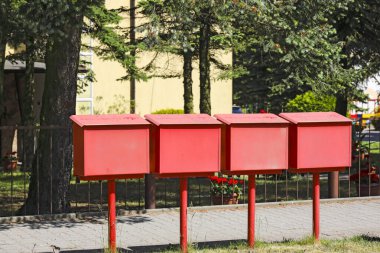 Ustronie Morskie, Polonya - 22 Mayıs 2024: Polonya Posta Ofisi 'nin kırmızı posta kutuları arka taraftan görüldü. Çimenlik ve kaldırım arasında yer alıyorlar..