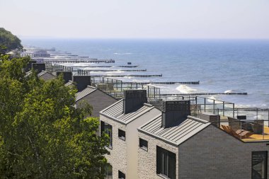 Ustronie Morskie, Polonya - 21 Mayıs 2024: Baltık Denizi kıyısında apartman blokları. Kıyı, denizde görünen ahşap dalgalarla korunuyor..