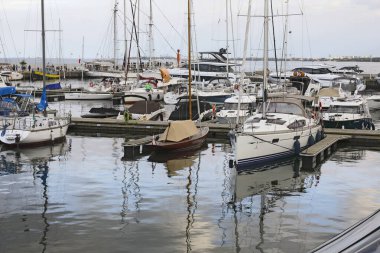 Sopot, Polonya - 6 Ekim 2024: Baltık Denizi 'nin en uzun tahta iskelesinin sonundaki yat limanında demirli yelkenliler. Gökyüzü burada bulutlu..