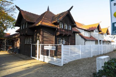 Sopot, Polonya - 9 Ekim 2024: Çitin arkasından görülen bir otelin ahşap cephesi. Binanın çatısı seramik fayanslarla kaplı..