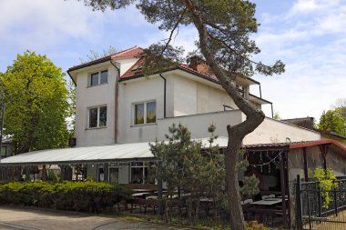 Mielno, Polonya - 15 Mayıs 2025: Kaldırımın kenarında bir ev bulunuyor. Bu kasaba, kiralık oda veren ya da turistlere restoran olarak hizmet veren pek çok müstakil eve ev sahipliği yapıyor..