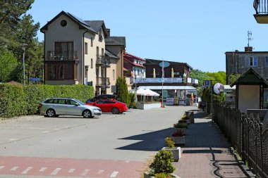 Mielno, Polonya - 20 Mayıs 2025: Sokakta trafik yok. Park yerlerinde sadece birkaç araba var. Evler uzaktan görülebilir..