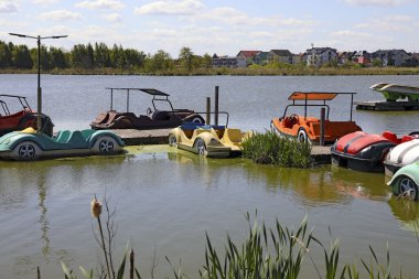 Mielno, Polonya - 12 Mayıs 2025: Araba şeklinde bu renkli pedal botlar Jamno Gölü kıyısındaki küçük bir marinada demirli..