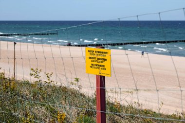 Mielno, Polonya - 12 Mayıs 2025: Baltık Denizi kıyısı boyunca bir kum tepeciği bölgesi doğa rezervi olarak belirlendi. Bir çit var ve Denizcilik Ofisi sarı bir tabela astı.. 