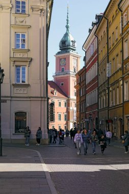 Varşova, Polonya - 4 Nisan 2025: Kalabalık Swietojanska Caddesi 'ndeki saat kulesi de dahil olmak üzere Kraliyet Kalesi' nin bir bölümünün görüntüsü.