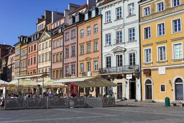 Varşova, Polonya - 4 Nisan 2025: Renkli apartmanlar Eski Şehir Meydanı 'ndaki sokak kafeleri ve restoranlar için zemin görevi görüyor. Bu restoranlar ziyaretçilere yiyecek ve içecek sunuyor..