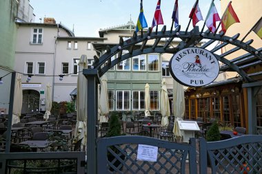 Sopot, Polonya - 7 Ekim 2024: Evin önünde çalışma saatlerinden önce boş koltukları olan bir açık hava restoranı var. Pinokio restoranının ve barın kapısı hala kapalı..