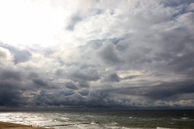 Baltık Denizi 'nin üzerinde asılı, koyu, kalın bulutlar gökyüzünü kaplıyor. Ufkun üstünde gördüğünüz gibi hava kararıyor. Bu manzara, Polonya 'nın deniz kıyısında bir kasabası olan Mielno' da çekildi..