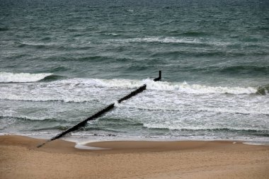 Rüzgarlı bir günde, Polonya 'nın Mielno kentindeki Baltık Denizi kıyısı boyunca hava ve dalgalar görülebilir. Dalgaların zararlı etkilerinden kıyıları korumak için dalgalar deniz tabanına doğru sürüklendi..