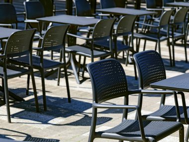 Kaldırımdaki kafedeki masalar ve sandalyeler siyah. Koltuklar boş ve dolu değil..