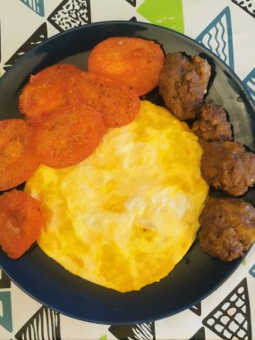 Omlet, domates dilimleri ve hamburgerli tabak.