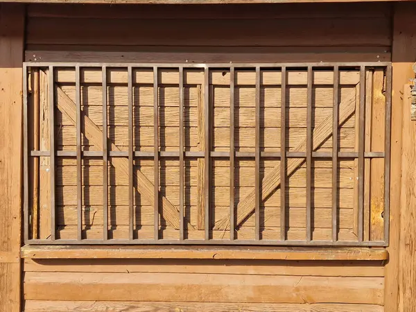 Parmaklıklı ahşap pencere, inşaattaki güvenlik ve estetik unsurlarını temsil ediyor.