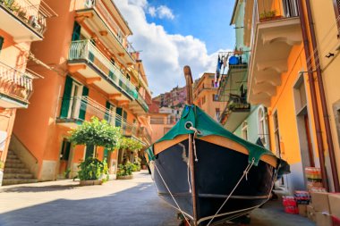 Geleneksel renkli evler ve İtalya 'nın Akdeniz kıyısındaki Cinque Terre' deki eski Manarola kasabasındaki dar bir sokakta geleneksel bir balıkçı teknesi.