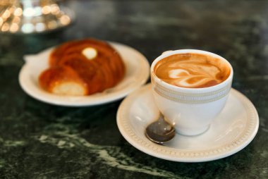 Bir fincan cappuccino ve bir kornetto, kahvaltıda kremalı İtalyan kruvasanı Centro Storico, Florence, İtalya 'da bir kafede.