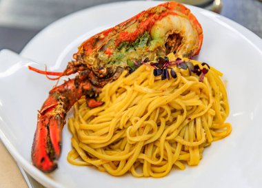 Fresh linguine pasta with a half lobster, decorated with micro greens, served on a white plate and at an Italian restaurant in Monte Carlo, Monaco
