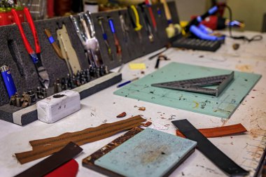Leather working tools on a work table in the back of a traditional artisanal leather workshop and studio in Centro Storico in Florence, Italy