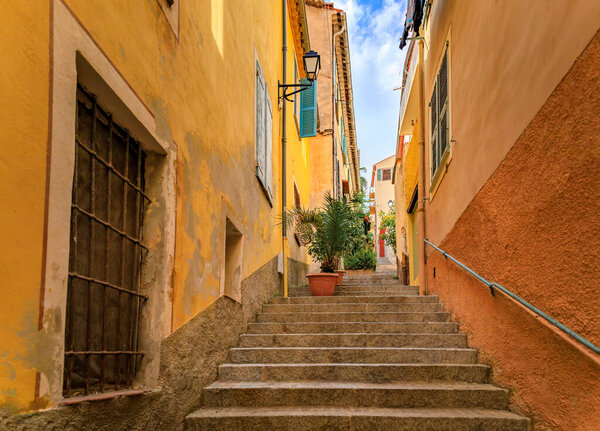 Stairs on a narrow street between traditional old terracotta houses in the Old Town of Villefranche sur Mer on the French Riviera, South of France