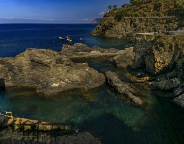 İtalya 'nın Cinque Terre kentindeki eski Manarola kasabasından gelen su üzerindeki kayık ve kayalıklarla Akdeniz' e gündüz görüşü